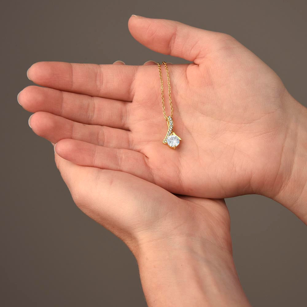 Yellow gold Alluring Beauty necklace pendant resting in a hand to show its size