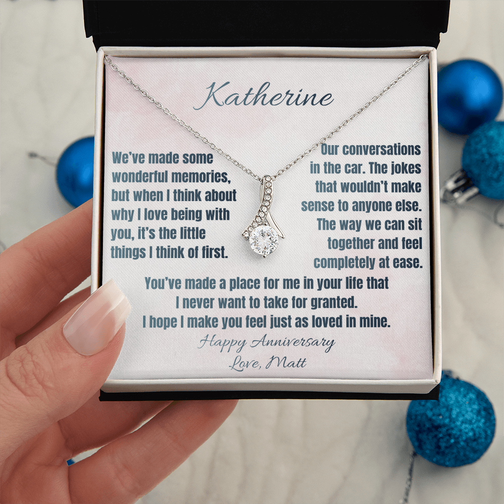 White gold anniversary necklace and Katherine message card held beside blue ornaments
