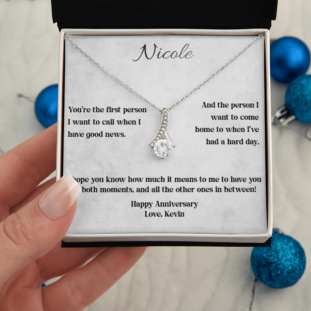 White gold Alluring Beauty anniversary necklace and Through Every Moment message card held beside blue ornaments
