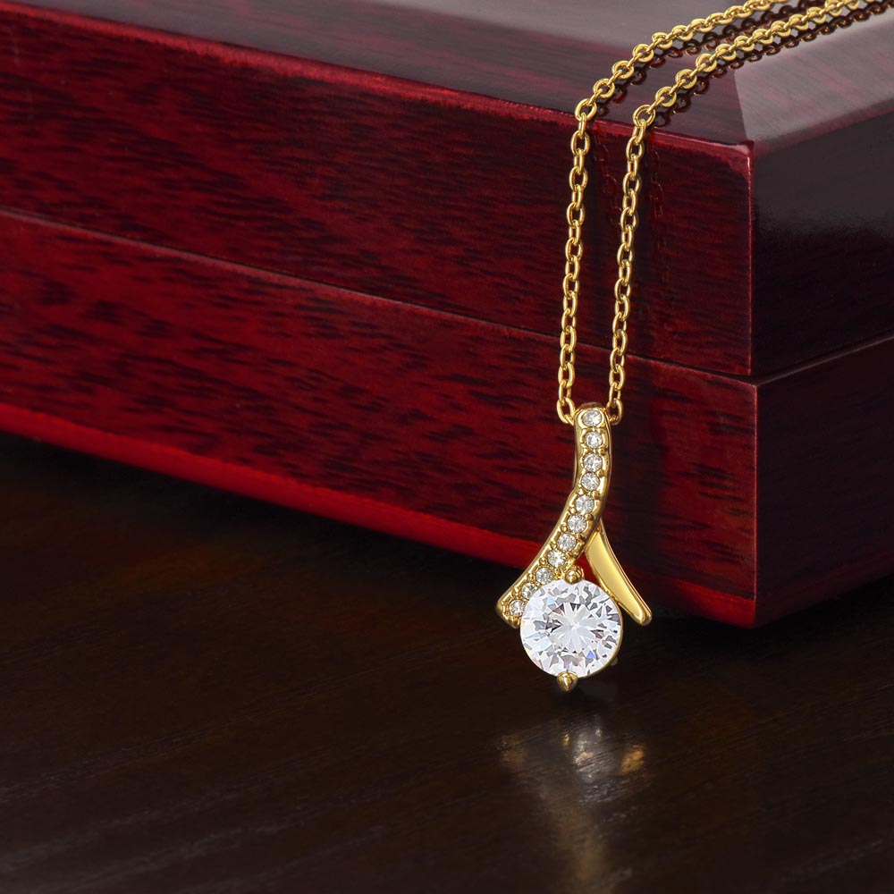 Yellow gold Alluring Beauty necklace pendant beside a mahogany gift box