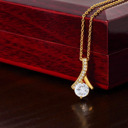 Yellow gold Alluring Beauty necklace pendant beside a mahogany gift box