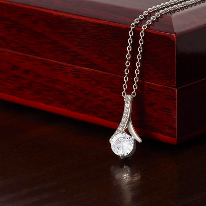White gold Alluring Beauty necklace pendant beside a mahogany gift box