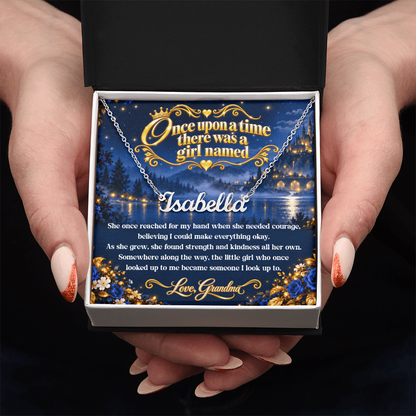 Hands presenting a silver-tone Isabella name necklace with a Once Upon a Time card from Grandma in an open black and white gift box.